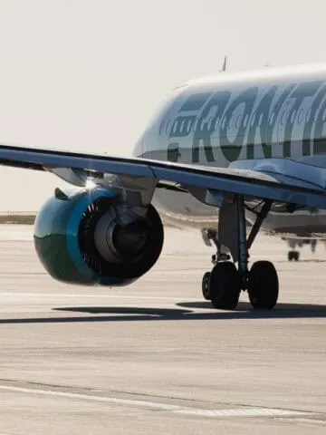 White plane with green lettering spelling out Frontier on runway
