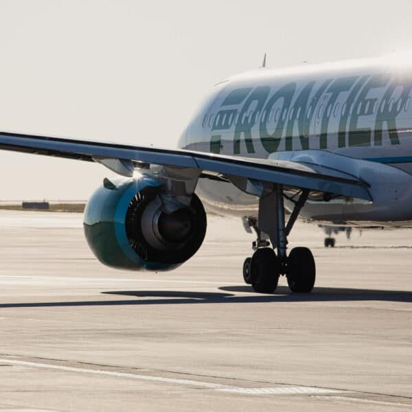 White plane with green lettering spelling out Frontier on runway