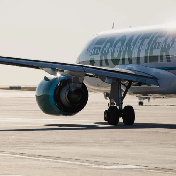 White plane with green lettering spelling out Frontier on runway