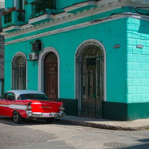 red 1950's coupe with white roof parked beside aquablue concrete building during daytime, Havanna, Cuba