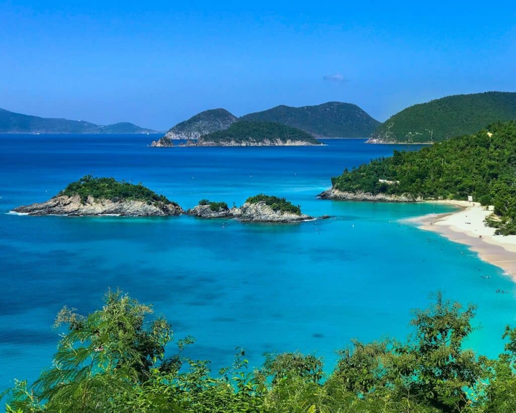green leafed trees and body of water; white sand beach with green tree topped islands in St Maarten