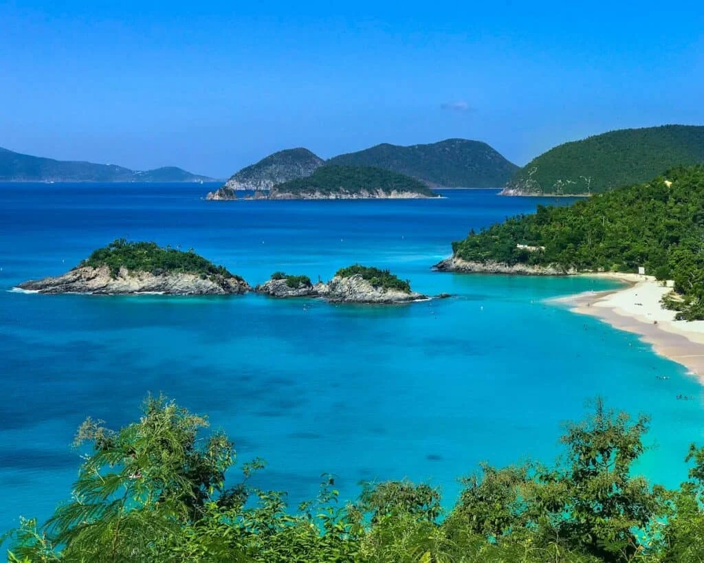 green leafed trees and body of water; white sand beach with green tree topped islands in St Maarten
