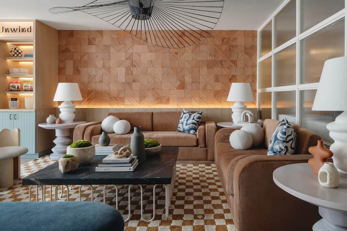 brown sofas, white lamps, black marble table against faux wood wall in hotel lobby