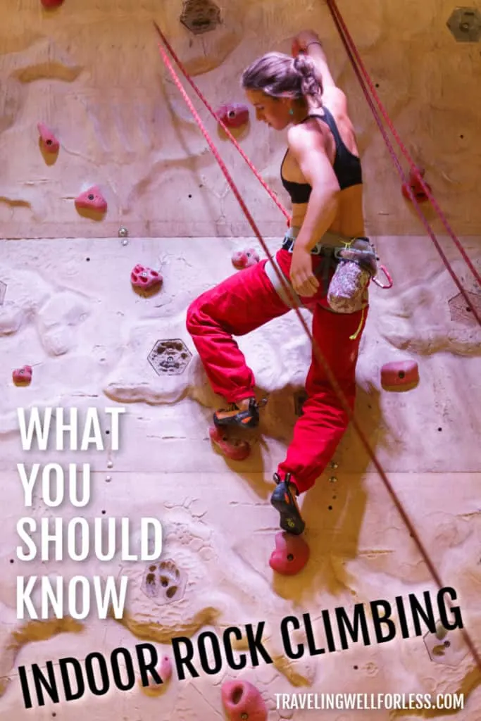 young woman in black sports bra and red pants climbing an indoor rock wall