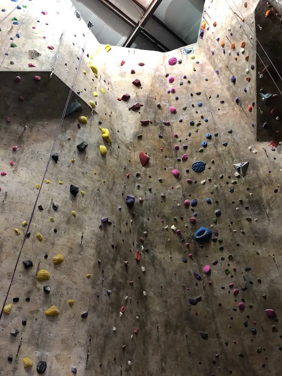 tall indoor rock climbing wall with various size and colored hand and foot holds